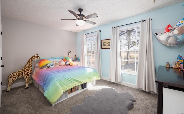 bedroom with carpet, a textured ceiling, baseboards, and a ceiling fan