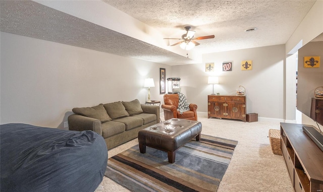 carpeted living room with ceiling fan, a textured ceiling, and baseboards