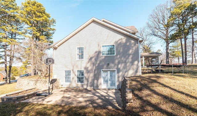 back of property with french doors, a patio, a trampoline, and a yard