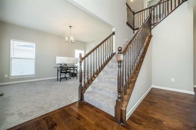 stairs with baseboards, wood finished floors, a chandelier, and carpet