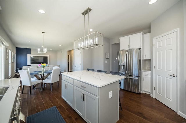 kitchen featuring stainless steel refrigerator with ice dispenser, dark wood-style floors, open floor plan, a kitchen island, and white cabinetry