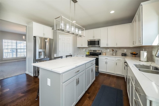 kitchen featuring stainless steel appliances, a sink, a center island, dark wood-style floors, and recessed lighting