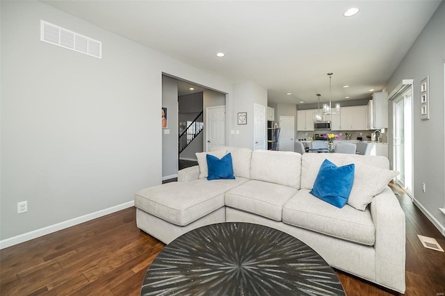 living room featuring dark wood-style flooring, stairs, baseboards, and recessed lighting