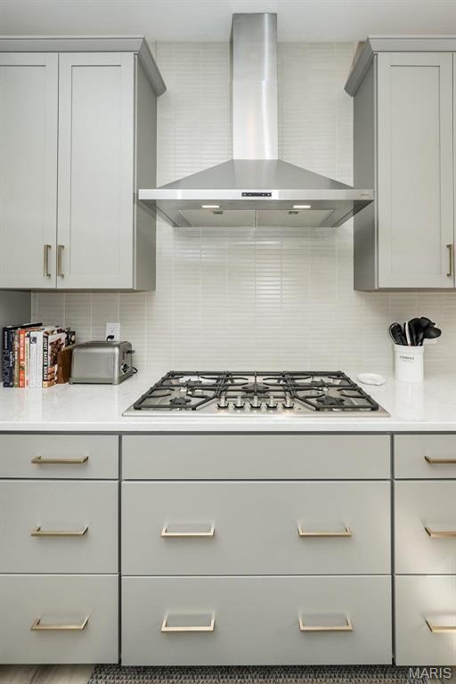 5019 Pacific Crest Trl, Cottleville, MO 63304 - kitchen with wall chimney range hood, stainless steel gas cooktop, tasteful backsplash, and light countertops