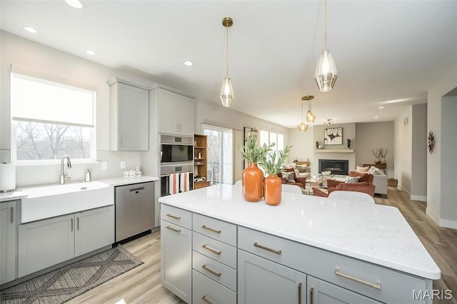 5019 Pacific Crest Trl, Cottleville, MO 63304 - kitchen with appliances with stainless steel finishes, gray cabinetry, a sink, light wood-style flooring, and backsplash