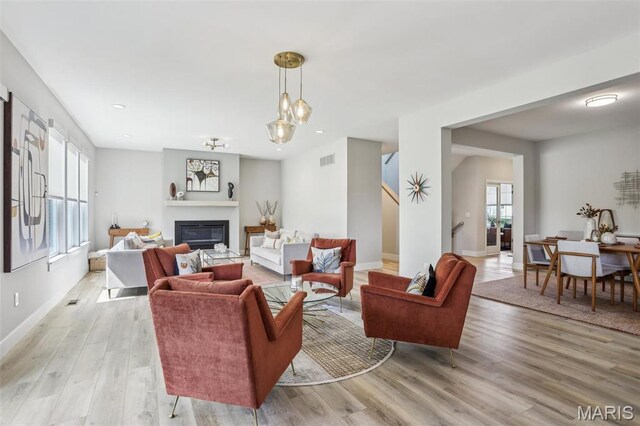 5019 Pacific Crest Trl, Cottleville, MO 63304 - living room featuring light wood-style flooring, stairs, a glass covered fireplace, baseboards, and recessed lighting