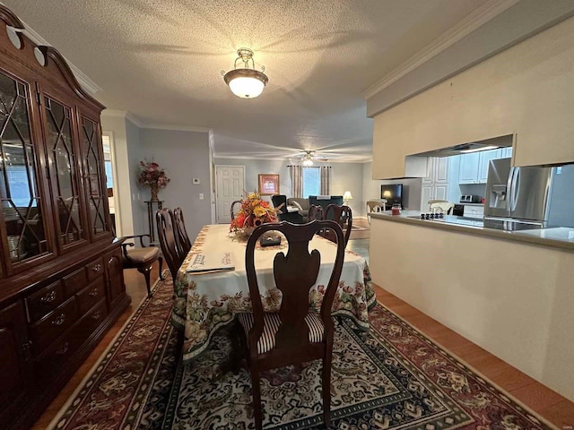 dining room with ornamental molding, wood finished floors, a ceiling fan, and a textured ceiling