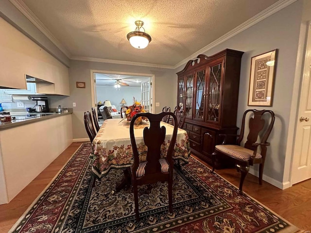 dining area featuring a textured ceiling, wood finished floors, ceiling fan, crown molding, and baseboards