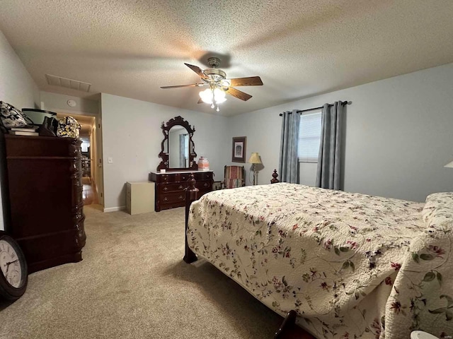bedroom featuring light colored carpet, a textured ceiling, a ceiling fan, and attic access