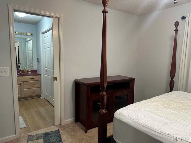 501 Forrest, Dexter, MO 63841 - bedroom featuring light colored carpet, baseboards, ensuite bathroom, and a textured ceiling