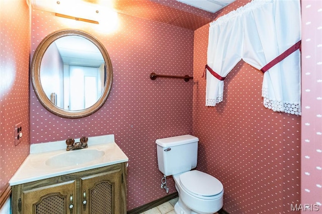 bathroom with wallpapered walls, toilet, and vanity