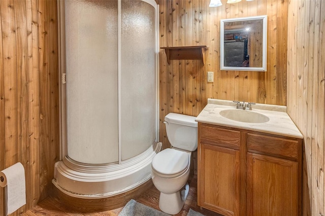 bathroom with a stall shower, toilet, wooden walls, and vanity