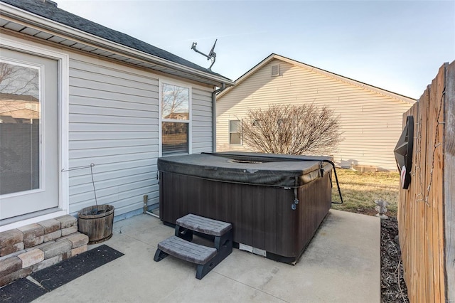 view of patio / terrace with a hot tub and fence