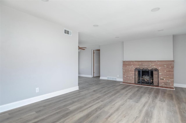 unfurnished living room featuring wood finished floors, a brick fireplace, and baseboards