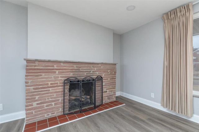 detailed view of wood finished floors, baseboards, and a fireplace