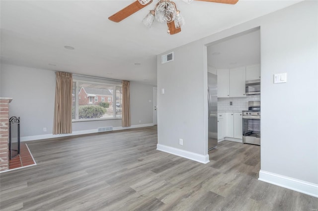 unfurnished living room with a ceiling fan, light wood-style floors, baseboards, and a brick fireplace