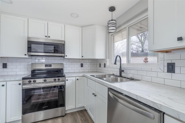 kitchen with stainless steel appliances, a sink, light countertops, white cabinets, and wood finished floors