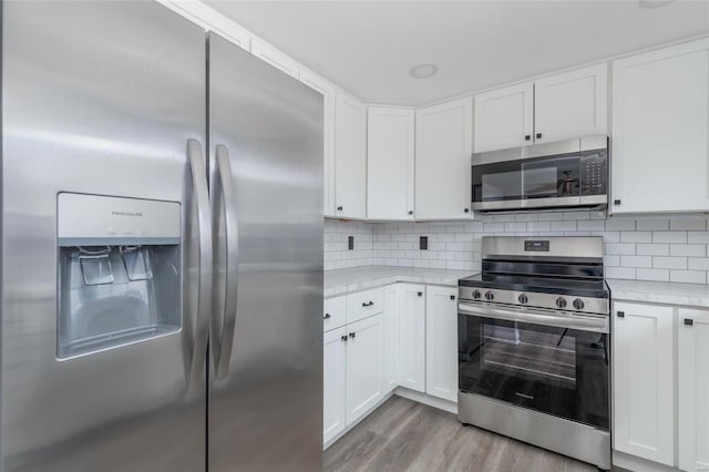 kitchen with stainless steel appliances, light countertops, and white cabinetry