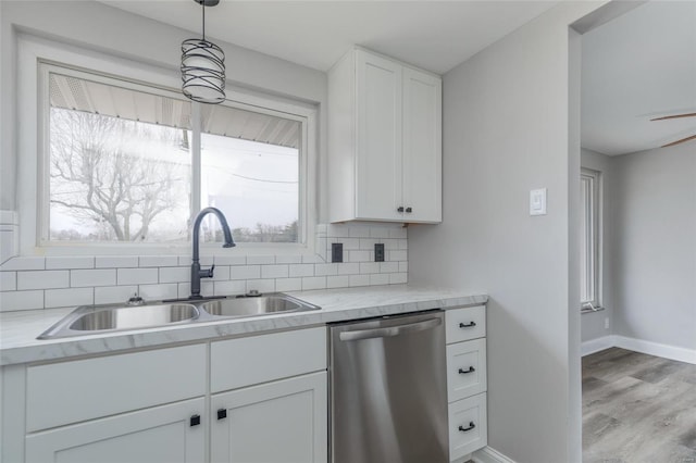 kitchen featuring dishwasher, a sink, tasteful backsplash, and white cabinetry