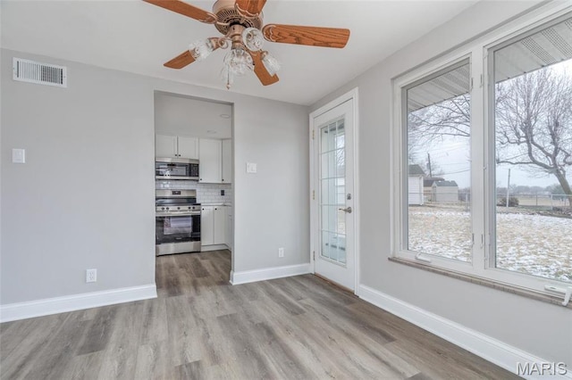 7080 Plainview Ave, Saint Louis, MO 63109 - unfurnished dining area with light wood-type flooring, a ceiling fan, and baseboards
