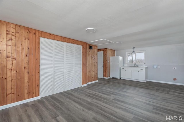 7080 Plainview Ave, Saint Louis, MO 63109 - unfurnished living room with dark wood-type flooring, baseboards, wood walls, and a sink