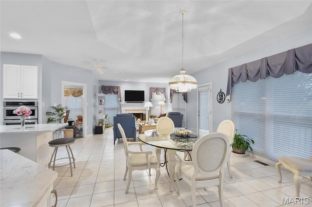12537 Clark Manor Cir, Creve Coeur, MO 63141 - dining area with light tile patterned floors, a ceiling fan, a fireplace, recessed lighting, and a chandelier