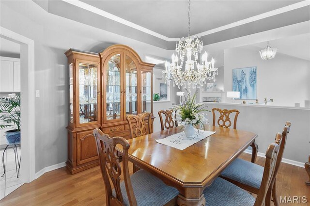 12537 Clark Manor Cir, Creve Coeur, MO 63141 - dining room featuring a chandelier, light wood-type flooring, a tray ceiling, and baseboards
