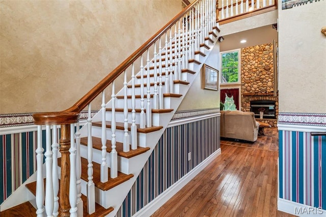 11400 State Road C, Hillsboro, MO 63050 - stairway featuring wood-type flooring, a fireplace, wallpapered walls, and a towering ceiling