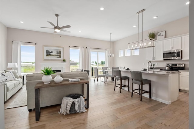 3248 River Breeze Ct, Saint Charles, MO 63301 - living room featuring a ceiling fan, a chandelier, recessed lighting, a fireplace, and light wood-type flooring