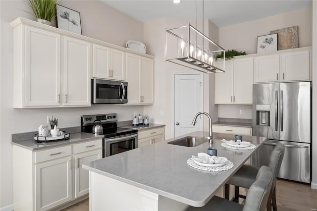 3248 River Breeze Ct, Saint Charles, MO 63301 - kitchen with appliances with stainless steel finishes, a sink, a breakfast bar area, white cabinetry, and recessed lighting