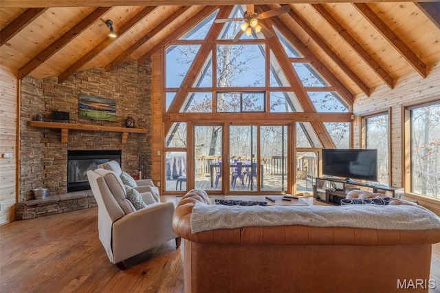 1758 Turrach Dr, Innsbrook, MO 63390 - living room with high vaulted ceiling, wood-type flooring, wooden ceiling with exposed beams, a stone fireplace, and ceiling fan