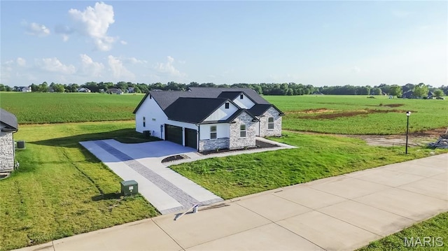 1002 Brianna Ct, Jerseyville, IL 62052 - view of front facade featuring stone siding, a view of countryside, concrete driveway, a garage, and a front yard