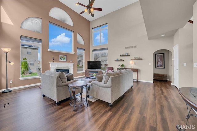 1101 Panda Ct, Wentzville, MO 63385 - living room with ceiling fan, baseboards, dark wood-style floors, a fireplace, and a towering ceiling