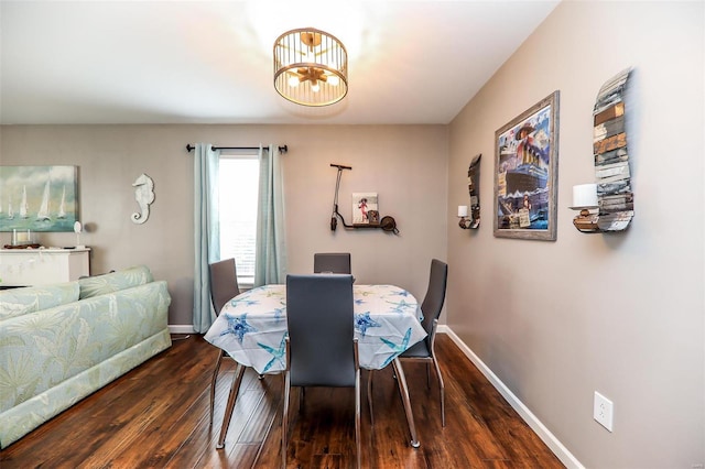 dining space with dark wood-style floors, a chandelier, and baseboards