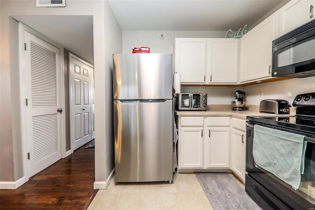 kitchen with black appliances, light countertops, white cabinets, baseboards, and light wood-style flooring