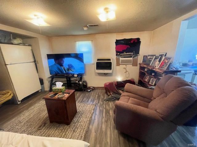 659 W 4th St, Lebanon, MO 65536 - living room with heating unit, a textured ceiling, and wood finished floors