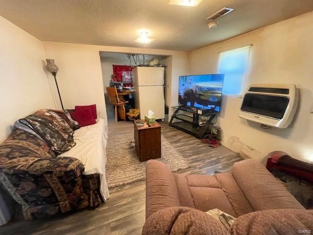 659 W 4th St, Lebanon, MO 65536 - living area featuring wood finished floors, a textured ceiling, and heating unit
