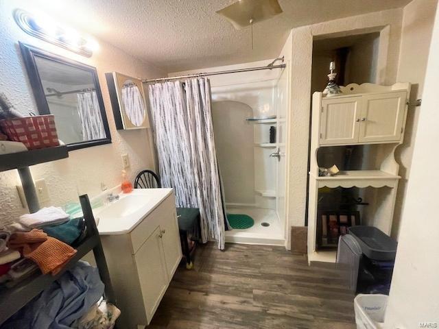 659 W 4th St, Lebanon, MO 65536 - full bathroom with wood finished floors, a shower stall, a textured ceiling, and vanity