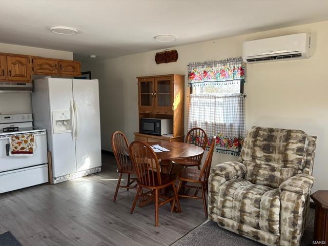 dining space with a wall mounted air conditioner and wood finished floors