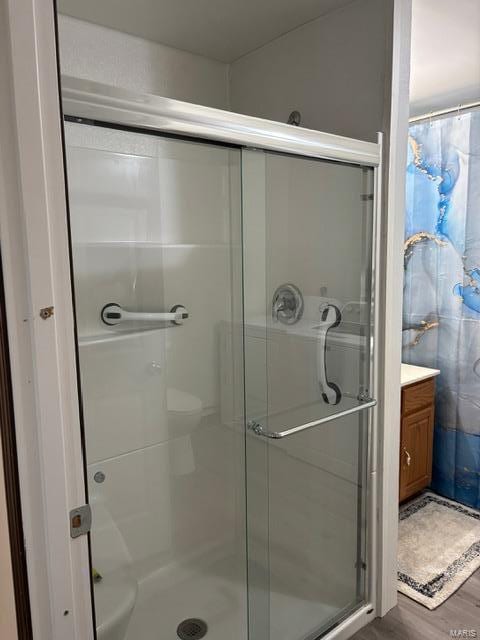 full bathroom with a stall shower, wood finished floors, and vanity