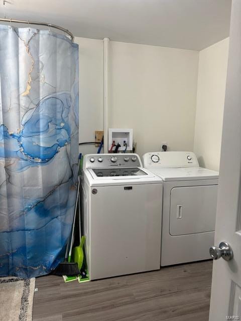 clothes washing area featuring washer and dryer and wood finished floors