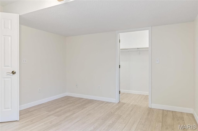 3216 E Leverett Ct, Alton, IL 62002 - unfurnished bedroom with light wood-style floors, a spacious closet, a textured ceiling, baseboards, and a closet