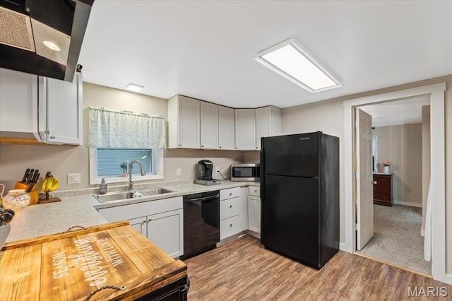 6405 S Ronnie Dr, Waterloo, IL 62298 - kitchen featuring black appliances, light countertops, light wood finished floors, white cabinets, and wall chimney exhaust hood
