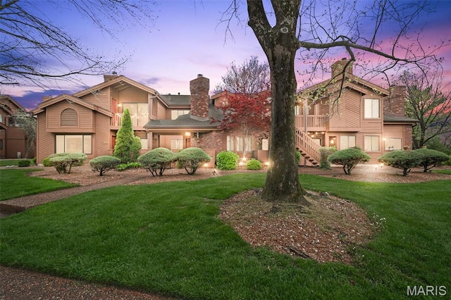 view of front of house with a front lawn, a chimney, and stairs