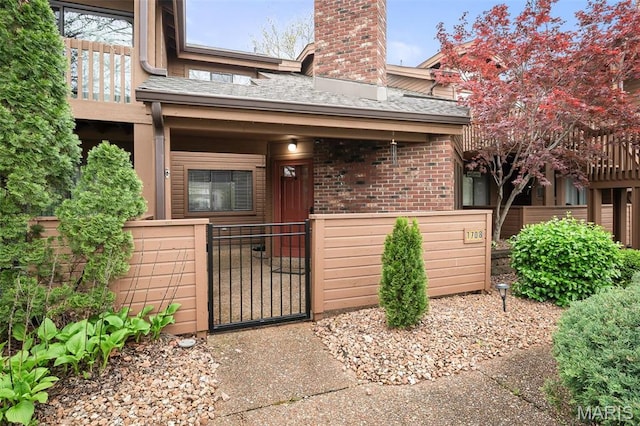 property entrance with fence, brick siding, a gate, a chimney, and covered porch