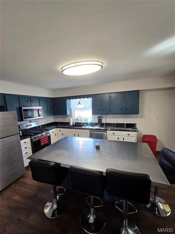 423 Virginia St, Granite City, IL 62040 - kitchen featuring stainless steel appliances, dark countertops, backsplash, and dark wood-style floors