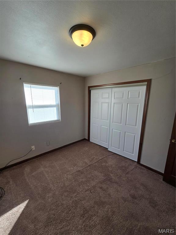 423 Virginia St, Granite City, IL 62040 - unfurnished bedroom featuring dark carpet, a closet, and baseboards