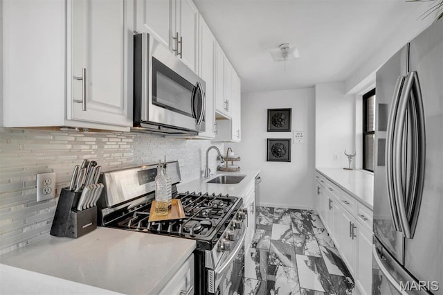 4466 W Pine Blvd Unit 8E, Saint Louis, MO 63108 - kitchen featuring appliances with stainless steel finishes, a sink, light marble finish flooring, light countertops, and white cabinetry