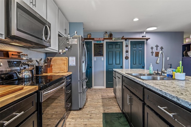 703 Locust St, Desloge, MO 63601 - kitchen with appliances with stainless steel finishes, a sink, light wood-style floors, white cabinets, and backsplash