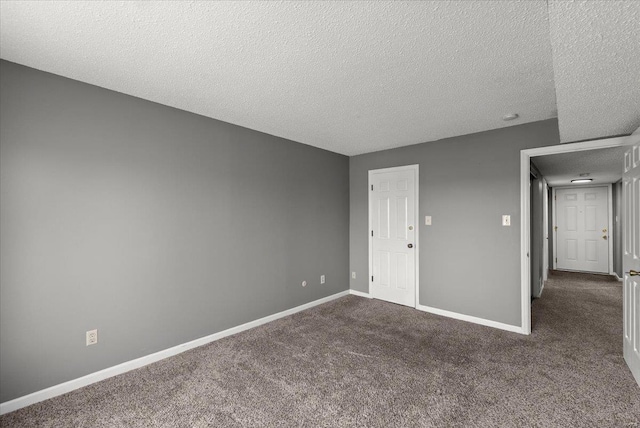 unfurnished bedroom with a textured ceiling, baseboards, and dark colored carpet